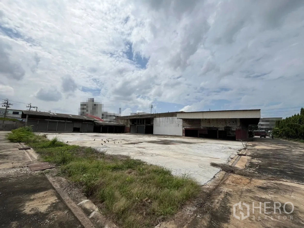 工厂 出租在Phra Pradaeng, Samut Prakan - 大面积硬化场地，多座仓库建筑与卷闸门。