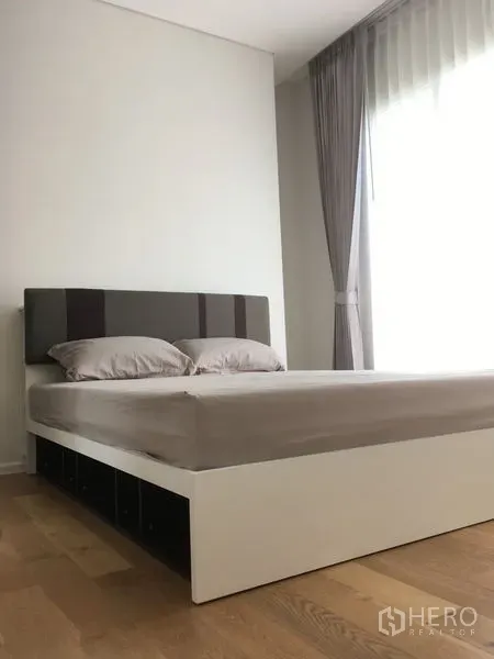 คอนโด ให้เช่าหรือขายในChatuchak, Bangkok - ห้องนอนสว่าง เตียงฐานขาว หัวเตียงสีเทา และม่านโปร่ง