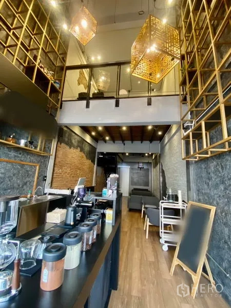 Shophouse for rent in Pathum Wan, Bangkok - Front counter with jars and equipment facing lounge seating beneath high ceilings and decorative pendant lights.