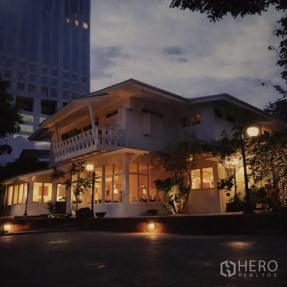 零售空间 for rent in Watthana, Bangkok - 夜间外立面照明明亮的两层零售楼，带阳台与落地窗，周边为高楼。