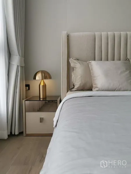 公寓 出租 - 床头特写：金色台灯、软包床头与浅色窗帘和床头柜。