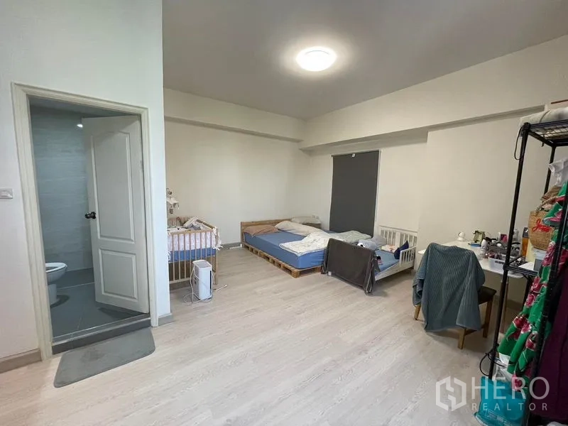 Condominium for sale in Sathon, Bangkok - Spacious master bedroom with ensuite bathroom, light wood floors and a crib.