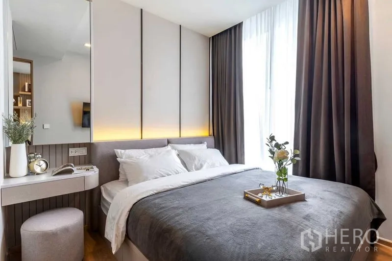 Condominium for rent in Watthana, Bangkok - Bedroom featuring a vanity corner and large window dressed with blackout curtains.