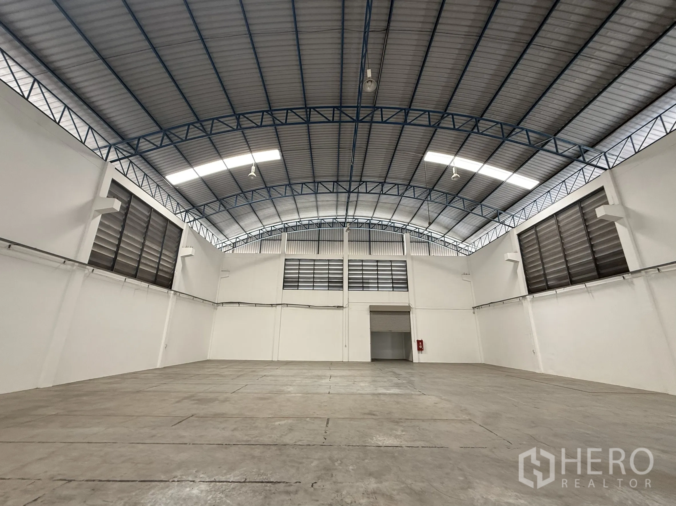 Warehouse for rent or sale in Bang Bo, Samut Prakan - Wide, empty warehouse under curved roof facing the rear loading door.