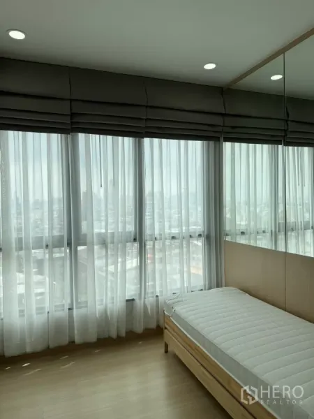 คอนโด ให้เช่าในKhlong Toei, Bangkok - มุมห้องนอนผนังกระจกพร้อมม่านโปร่งและเตียงเดี่ยว รับแสงธรรมชาติ