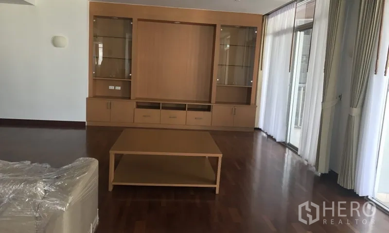 อพาร์ทเมนท์ ให้เช่าในWatthana, Bangkok - ห้องนั่งเล่นมีตู้โชว์บิวท์อินไม้และโต๊ะกลาง ข้างประตูระเบียง