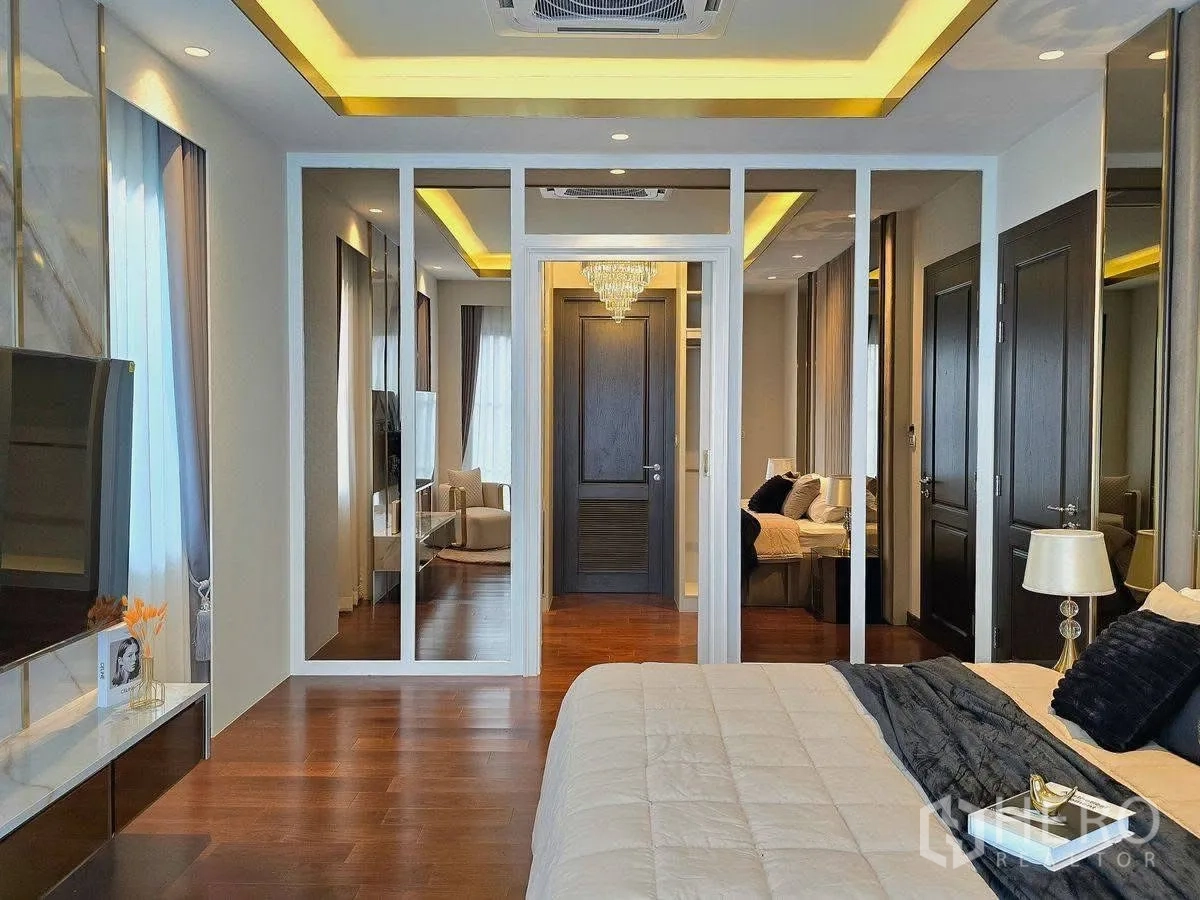Detached House for rent or sale in Bang Phli, Samut Prakan - Master bedroom view to mirrored wardrobe and hallway with recessed lights and warm tones.