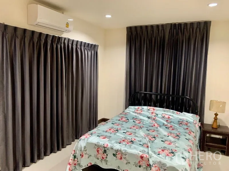 Detached House for rent in Khlong Sam Wa, Bangkok - Corner bedroom with large windows, AC, and dark curtains surrounding a double bed.