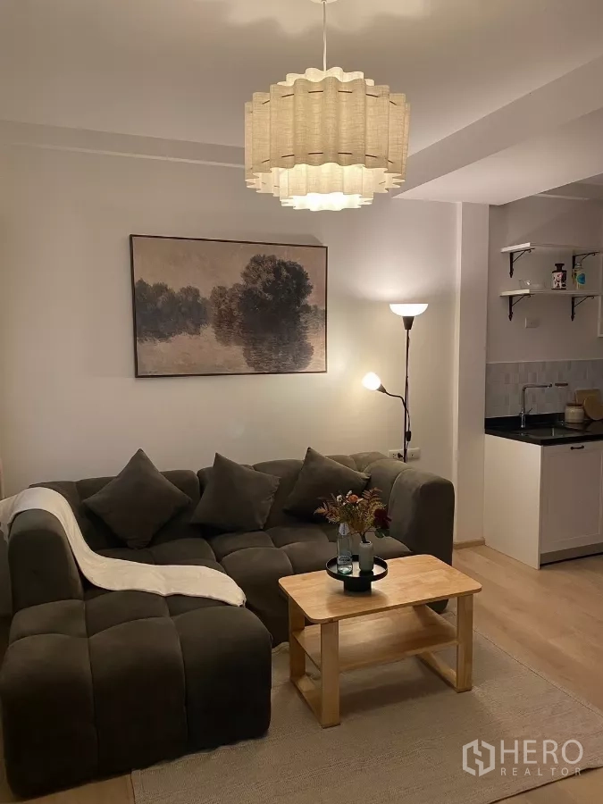 联排别墅 出租在Prawet, Bangkok - 暖色灯光下的客厅，沙发与吊灯。