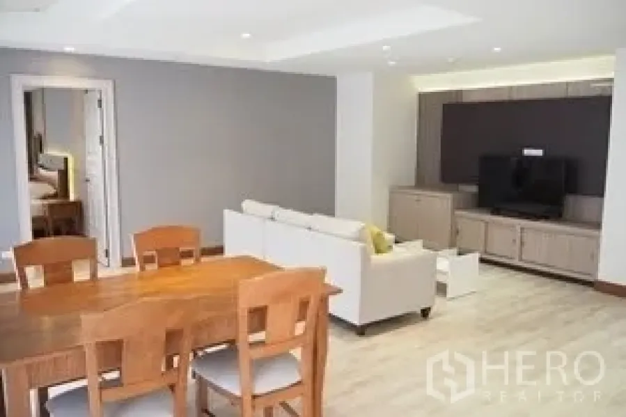 Condominium for rent in Pathum Wan, Bangkok - Pathum Wan condo open-plan living and dining with wood floors, sofa and TV wall.