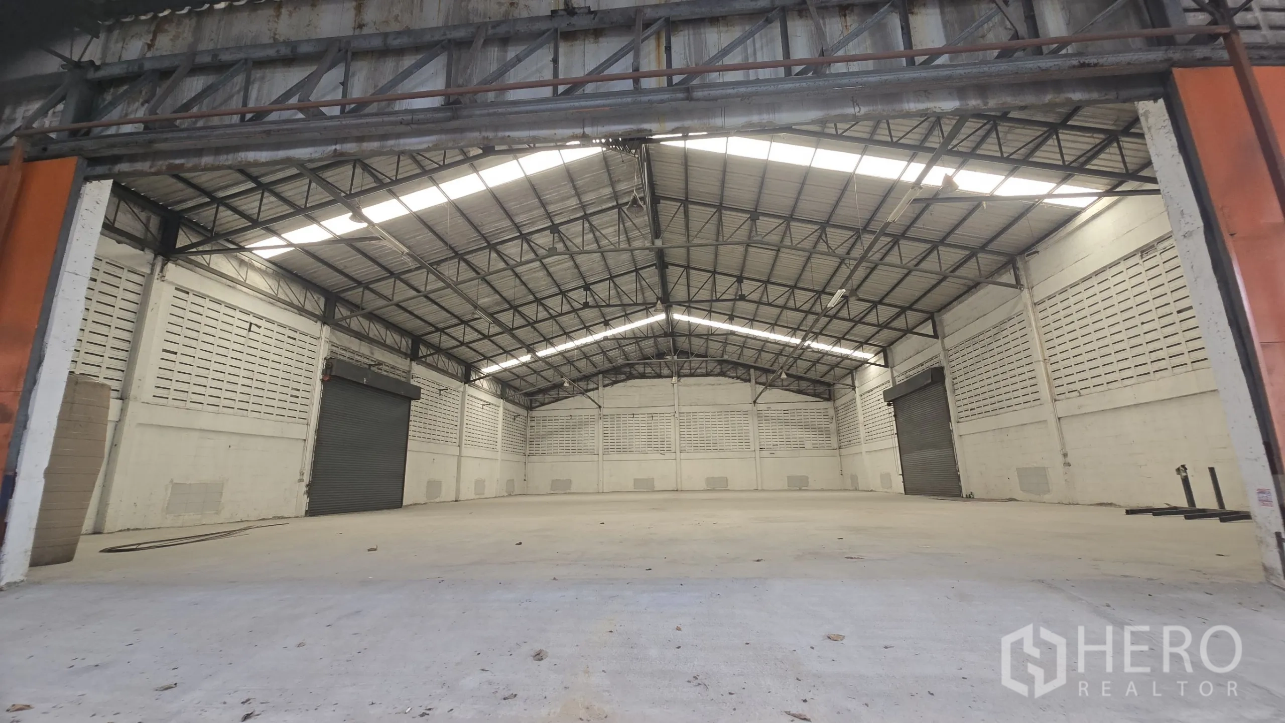 Warehouse for rent in Khlong Sam Wa, Bangkok - Spacious warehouse interior with high gable steel roof, skylights and twin roller shutters.
