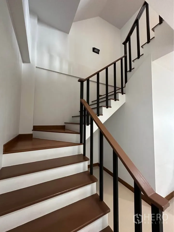 Townhouse for rent in Pak Kret, Nonthaburi - Staircase with wooden treads and black handrails connecting multiple levels.