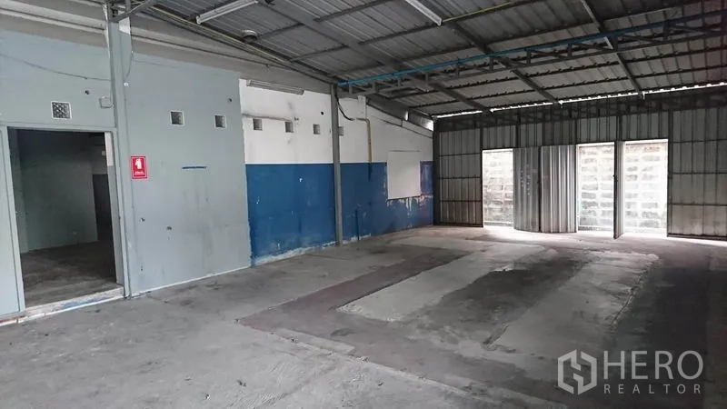 货栈 出租在Lak Si, Bangkok - 仓库内部开放式布局，水泥地面，蓝色墙面与金属推拉门。