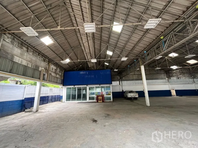 Warehouse for rent in Phra Khanong, Bangkok - Spacious warehouse interior with high steel-truss ceiling, skylights, and glass-fronted office.