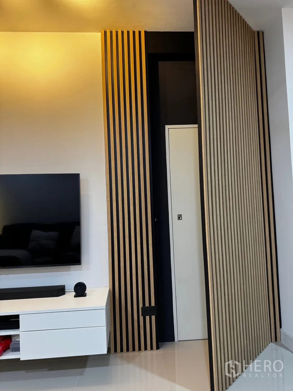 Townhouse for rent in Bang Phli, Samut Prakan - TV wall with wooden slat feature panels and a white media console.