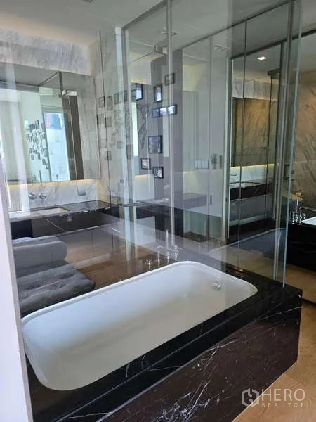 公寓 出租或出售在Bang Rak, Bangkok - 豪华浴室，玻璃隔断与白色浴缸，黑色大理石台。