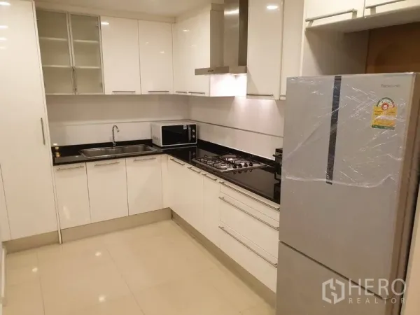 คอนโด ให้เช่าในWatthana, Bangkok - ครัวรูปตัวแอลโทนขาวสมัยใหม่ มีเตาแก๊สพร้อมฮูด อ่างล้างจาน ไมโครเวฟ และตู้เย็นขนาดใหญ่