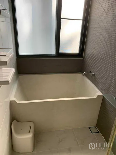 คอนโด ให้เช่าในWatthana, Bangkok - ห้องน้ำสมัยใหม่พร้อมอ่างอาบน้ำลึก หน้าต่างกระจกฝ้า และผนังกระเบื้องสีเทา