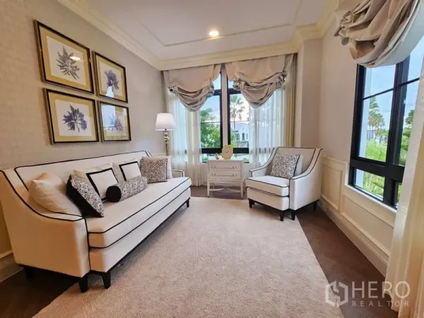 Detached House for rent or sale in Saphan Sung, Bangkok - Bright sitting room with a sofa, two armchairs and large windows overlooking greenery.