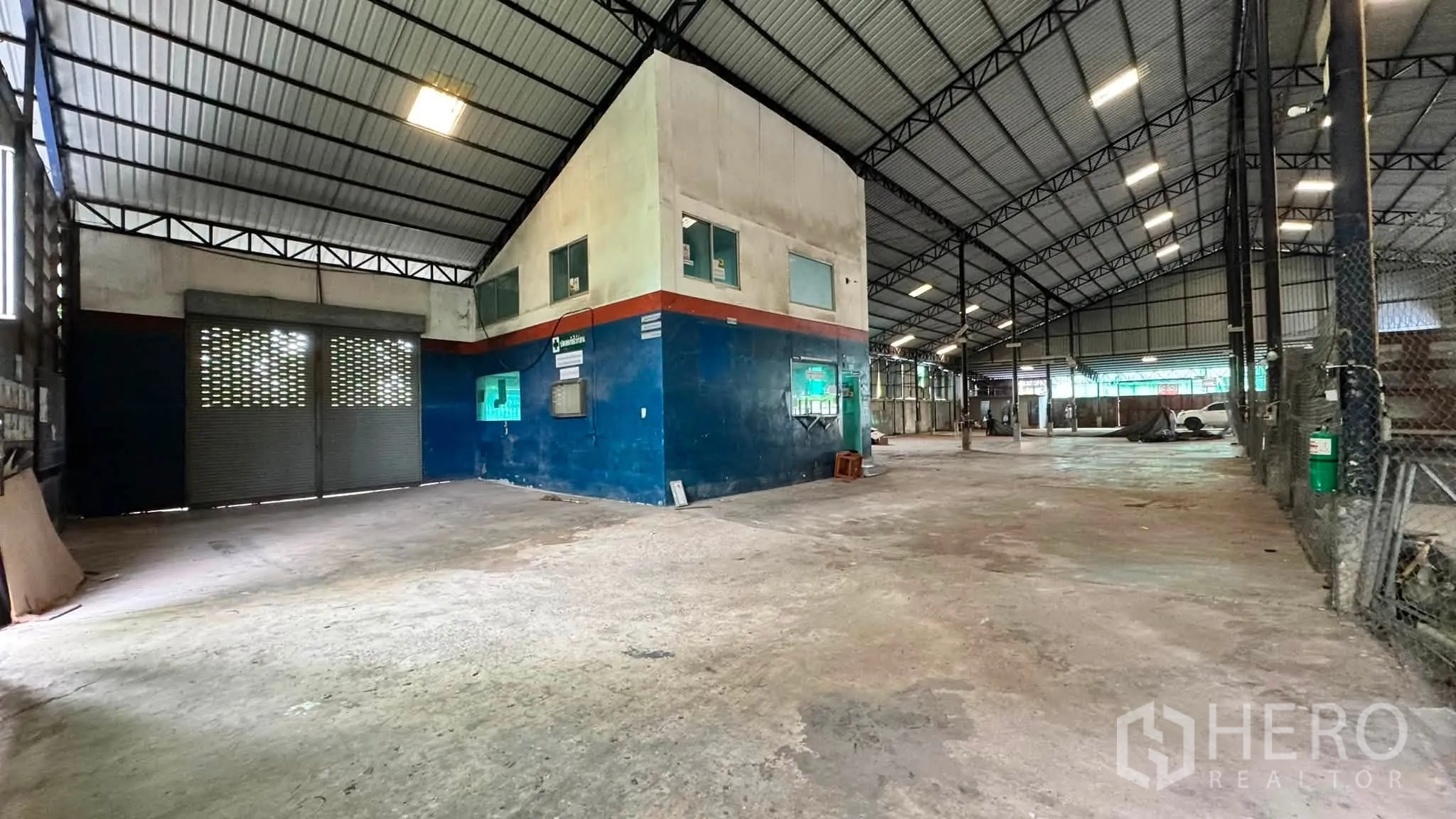 Warehouse for rent in Bang Khen, Bangkok - Warehouse bay showing internal office block, roller shutter door, and concrete surfaces.