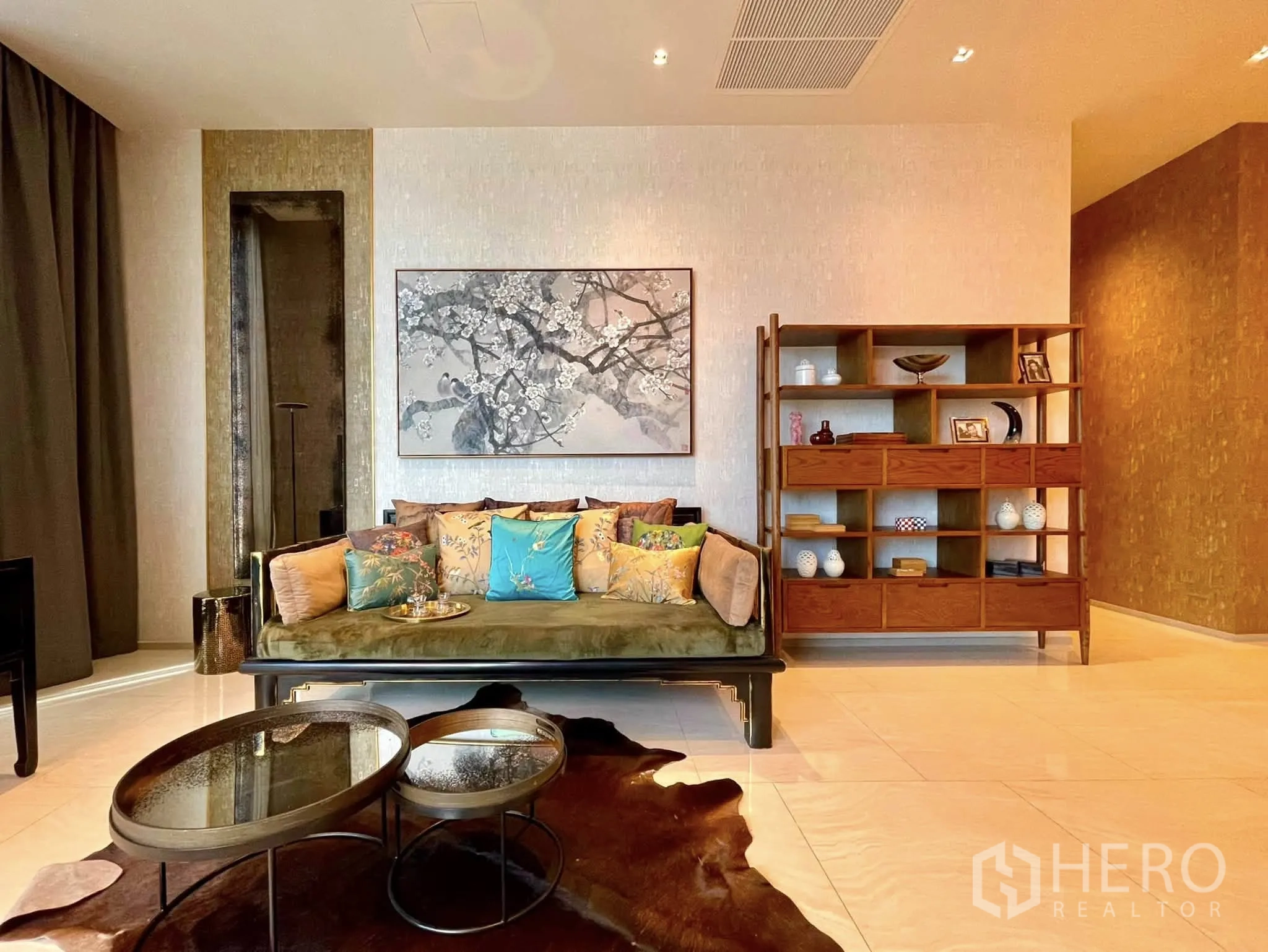 Condominium for rent in Bang Rak, Bangkok - Stylish living room with sofa, wall art, shelving and nested coffee tables.