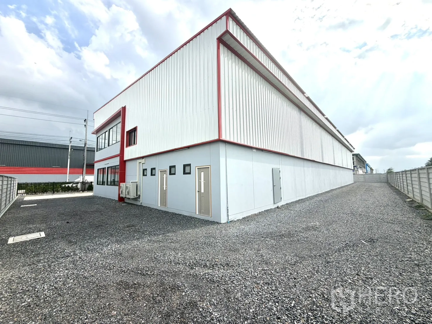 Factory for rent or sale in Lam Luk Ka, Pathum Thani - Rear service yard with gravel surface and utility doors.
