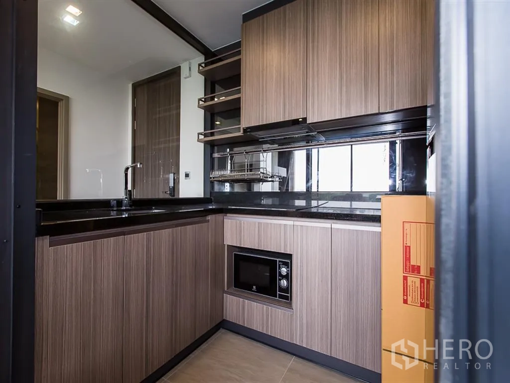 คอนโด for rent in Watthana, Bangkok - ครัวรูปตัวแอล ตู้ไม้ เคาน์เตอร์หินสีดำ อ่างล้างจาน และไมโครเวฟบิลท์อิน