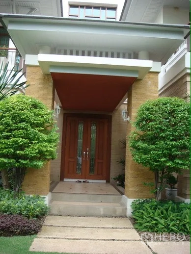 Detached House for rent or sale in Suan Luang, Bangkok - Covered front porch with double wooden entry doors and manicured shrubs.