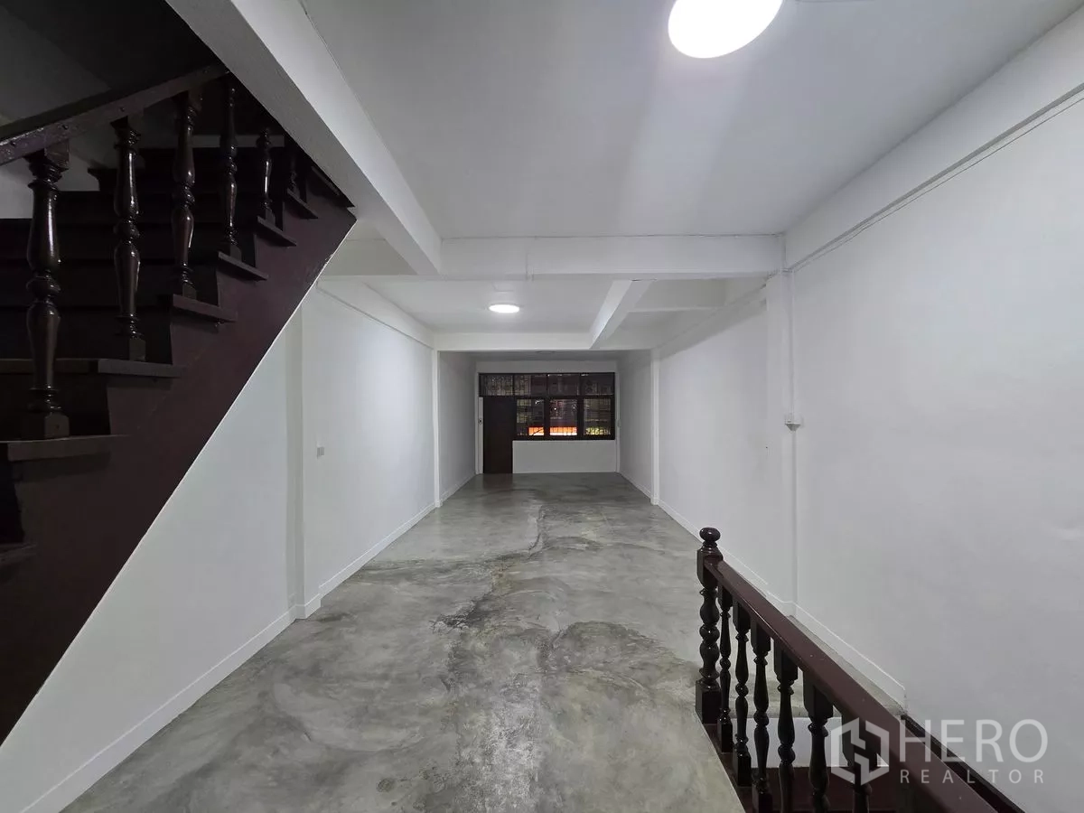 店屋 出租在Watthana, Bangkok - 室内视角：木楼梯与宽敞的混凝土地面
