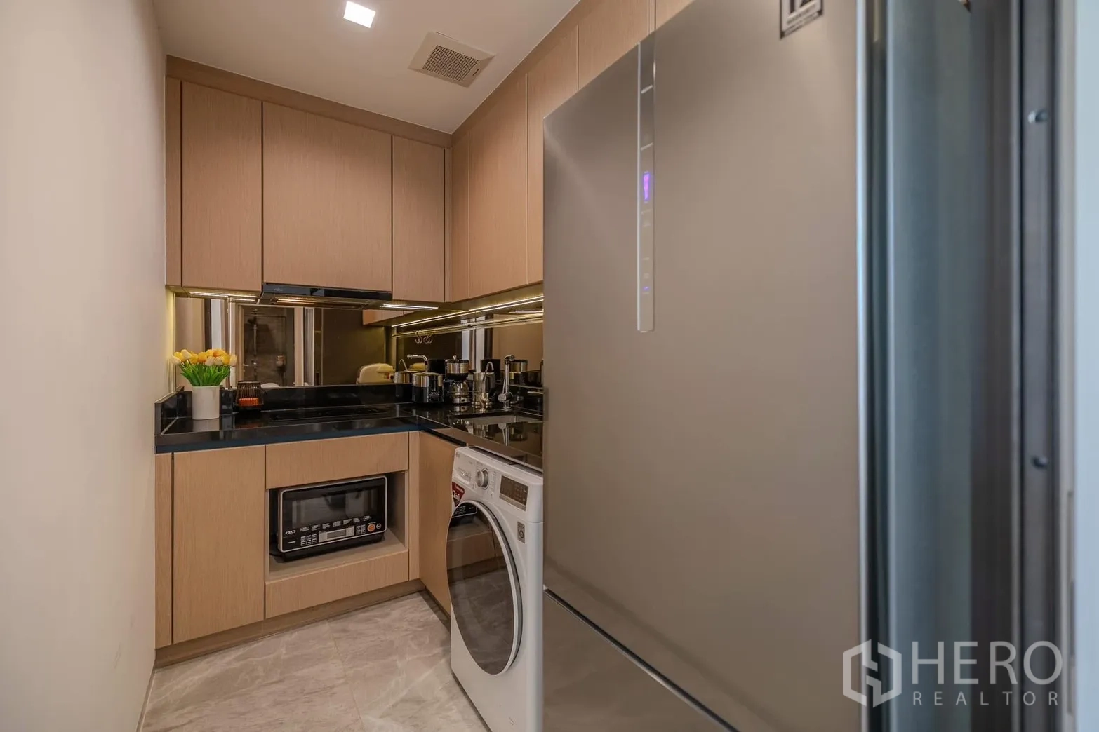Condominium for rent in Watthana, Bangkok - Compact kitchen with built-in cabinets, black countertop, refrigerator and washing machine.