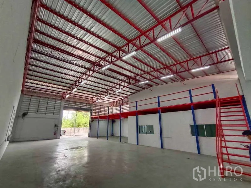 Warehouse for rent in Lat Krabang, Bangkok - Open-plan storage space facing the shutter door with a long mezzanine walkway.