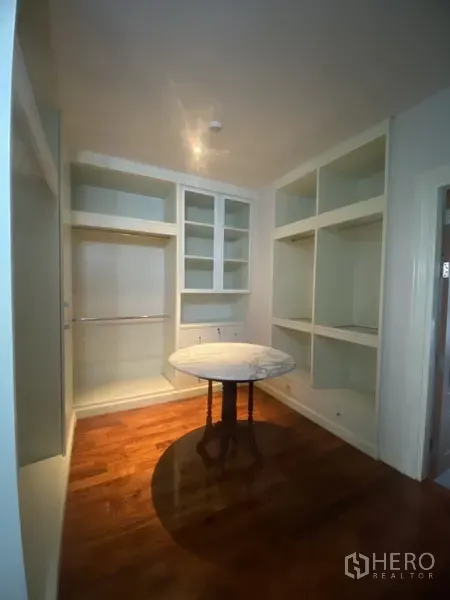 Apartment for rent in Pathum Wan, Bangkok - Walk-in closet featuring built-in shelving and hanging space on warm wood flooring.