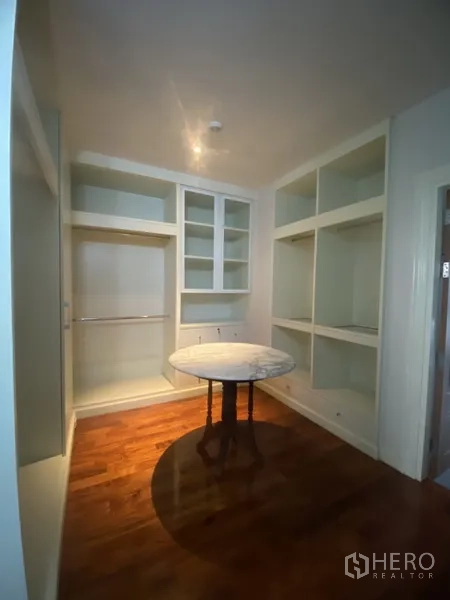 Apartment for rent in Pathum Wan, Bangkok - Walk-in closet featuring built-in shelving and hanging space on warm wood flooring.
