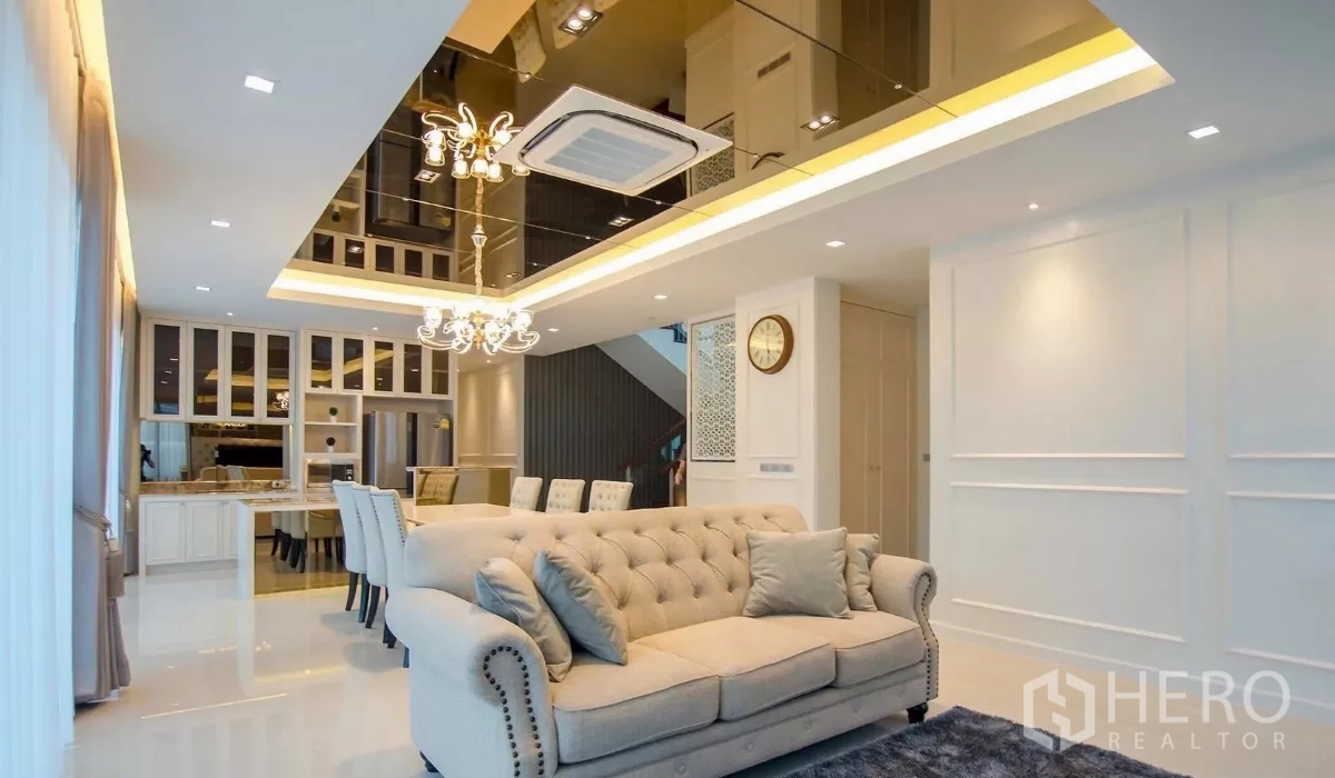 Detached House for rent in Bang Bon, Bangkok - Bright open-plan living room with tufted sofa, chandelier and ceiling cassette air-conditioner.