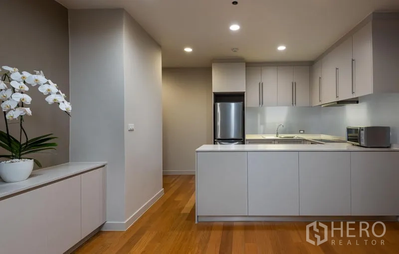 Condominium for rent in Bang Kho Laem, Bangkok - Sleek white kitchen with stainless refrigerator and ample cabinetry.