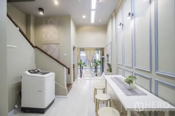 ทาวน์เฮาส์ ให้เช่าในKhlong Toei, Bangkok - โถงรับแขกเพดานสูง มีบันได โต๊ะยาว และหน้าต่างเปิดสู่ระเบียงเล็ก