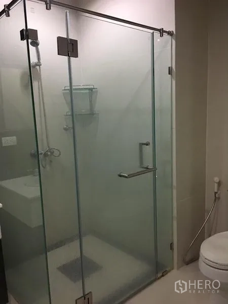 คอนโด ให้เช่าในPathum Wan, Bangkok - ห้องน้ำสมัยใหม่พร้อมตู้กระจกกั้นอาบน้ำ ถัดจากอ่างล้างหน้าและโถสุขภัณฑ์สีขาว