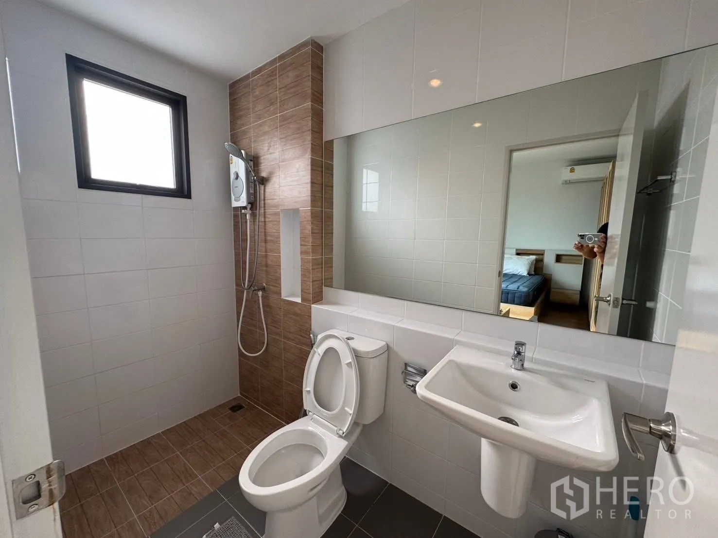 Townhouse for rent in Bang Phli, Samut Prakan - Bathroom with walk-in shower, white basin, toilet, and a wide mirror.