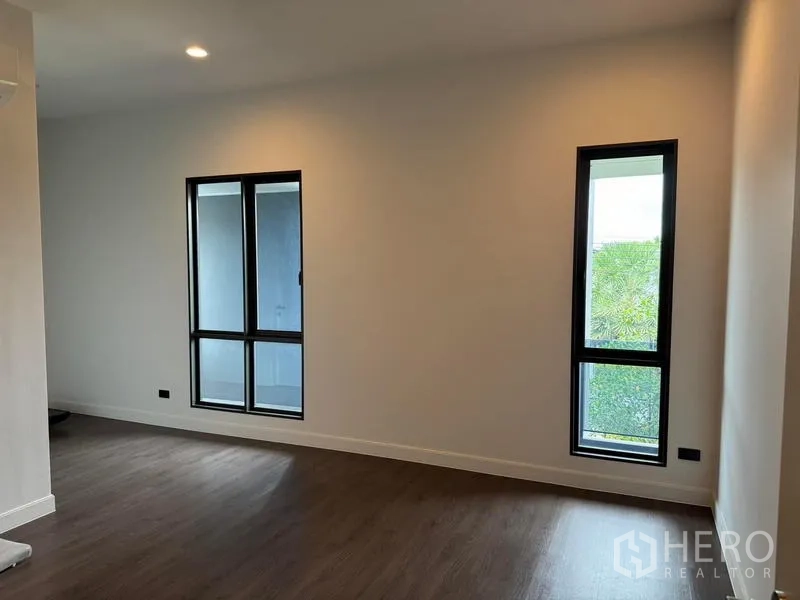 Detached House for rent in Bang Kapi, Bangkok - Empty room with wood floors and slim black‑framed windows ready for customization.