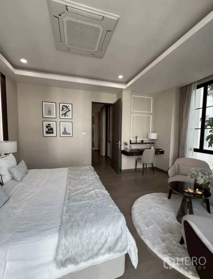 独立式住宅 出租在Lat Phrao, Bangkok - 宽敞主卧套房，含书桌与休闲椅，圆形地毯点缀。