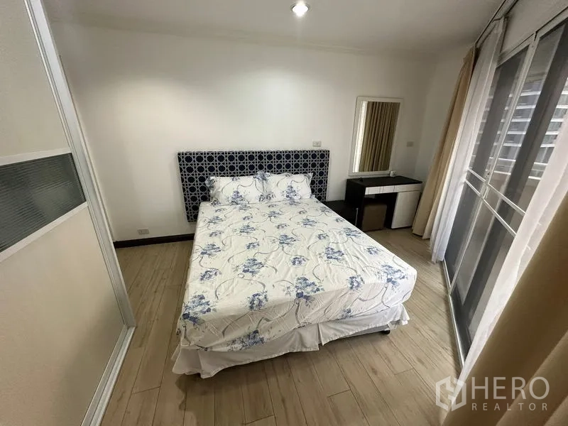 คอนโด ให้เช่าในWatthana, Bangkok - ห้องนอนคอนโดสว่าง เตียงควีน หัวเตียงลาย โต๊ะเครื่องแป้ง และประตูกระจกสไลด์ออกระเบียง ในเขตวัฒนา กรุงเทพฯ