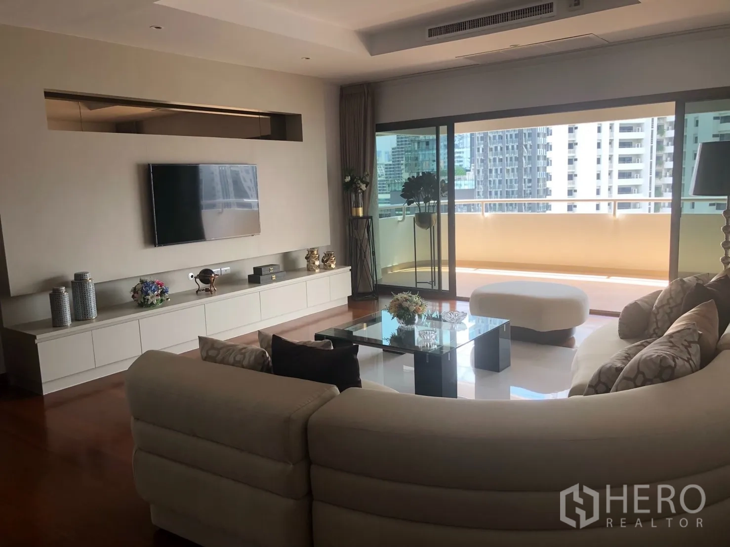 คอนโด ให้เช่าในBangkok - พื้นที่นั่งเล่นสว่าง ผนังทีวี ประตูบานเลื่อนออกสู่ระเบียงชมเมืองขนาดใหญ่