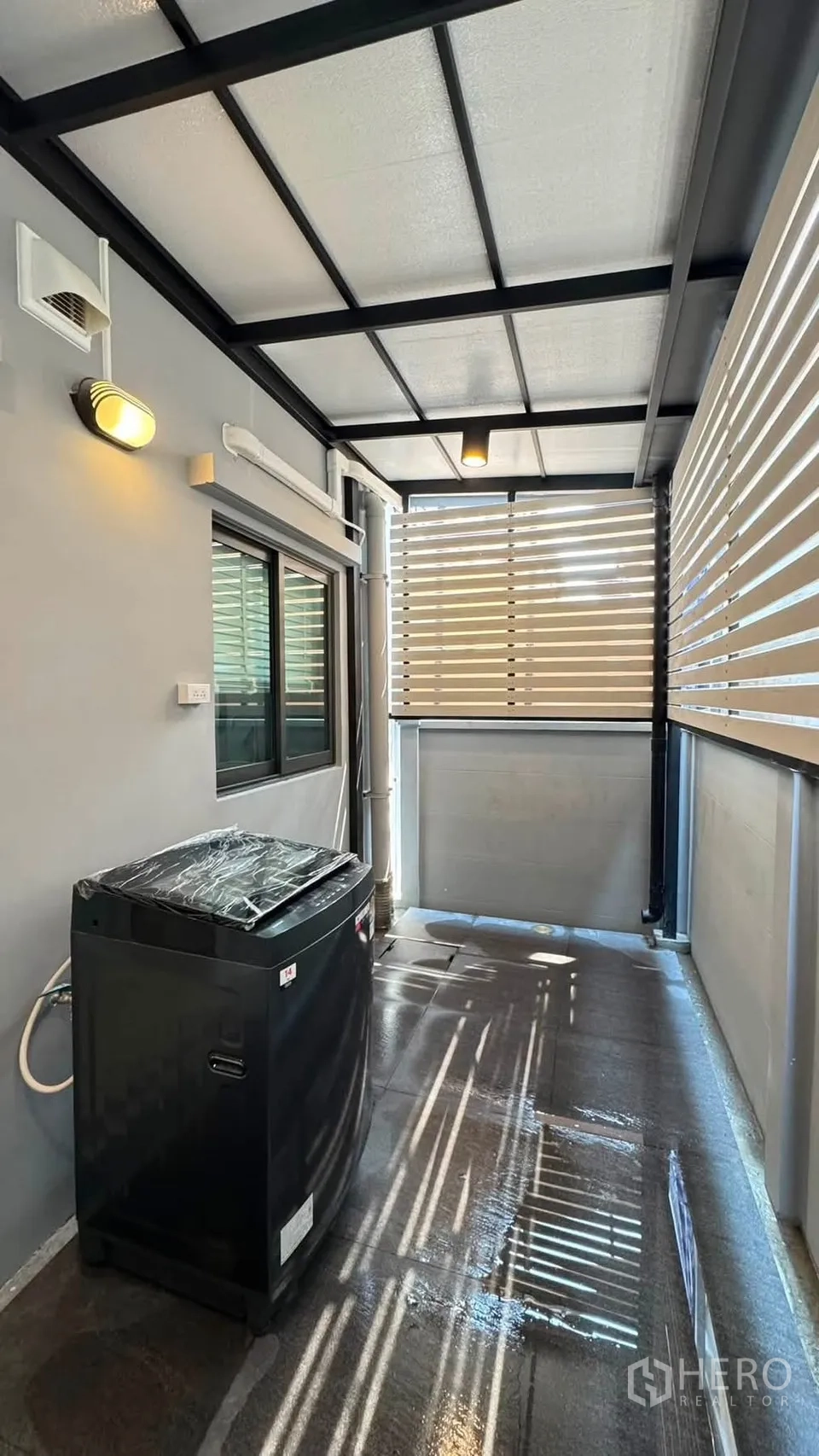 Townhouse for rent in Bang Phli, Samut Prakan - Covered utility area with washing machine, slatted privacy screens and ceiling lights.