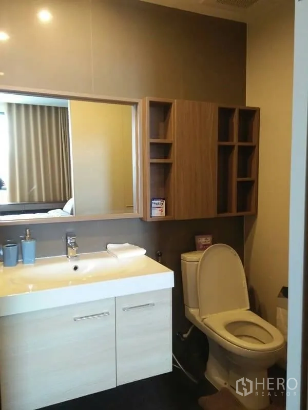 Condominium for rent in Huai Khwang, Bangkok - Bathroom with wide vanity, large mirror cabinets and toilet for ample storage.