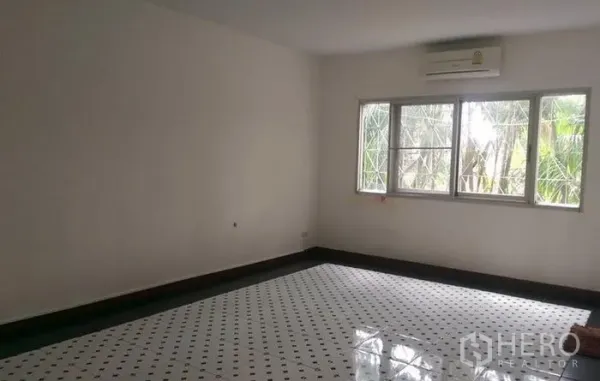 Townhouse for rent in Wang Thonglang, Bangkok - Bright room with patterned tile floor, large window and wall AC in a Wang Thonglang townhouse.