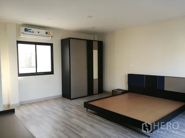 Townhouse for rent in Saphan Sung, Bangkok - Spacious master bedroom with platform bed, wardrobe, and air conditioner.