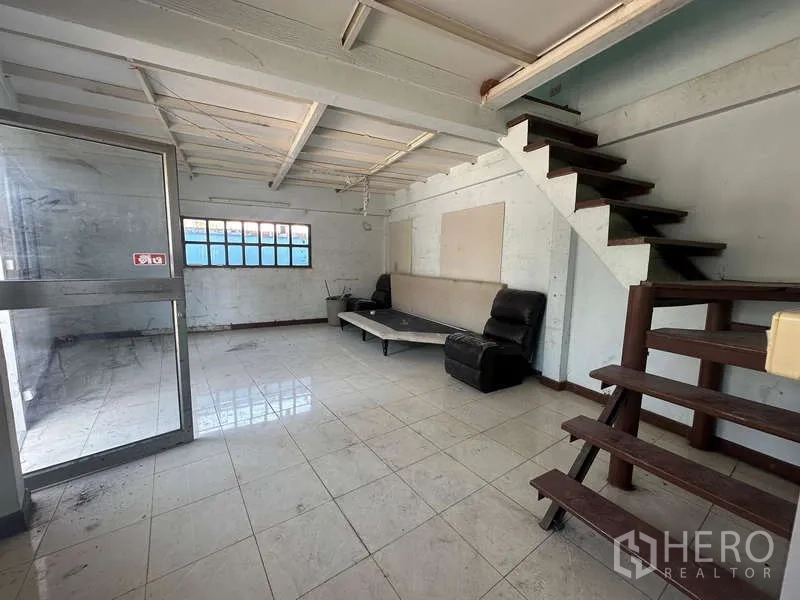 Warehouse for rent in Suan Luang, Bangkok - Ground-floor reception or break area with tiled floor, glass door and wooden stairs.