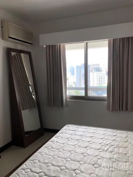 Condominium for rent in Watthana, Bangkok - Bedroom with large window, city view, full-length mirror, and soft curtains.