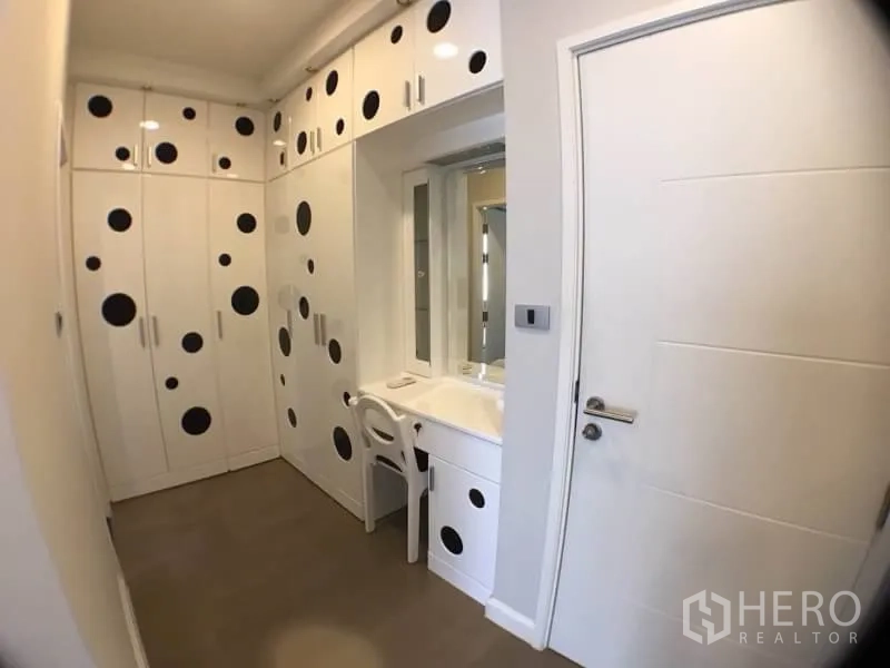 Condominium for rent in Khlong Toei, Bangkok - Dressing room with built-in white wardrobes and a makeup vanity.