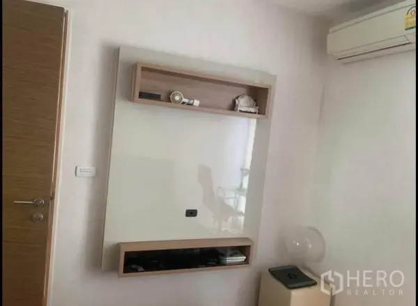 公寓 出售在Phaya Thai, Bangkok - 白色房间内的墙装电视面板与置物架，搭配空调机。